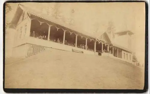 Fotografie J. Moegle, Thun, unbekannter Ort, Leute schauen aus einem Langhaus mit Turm