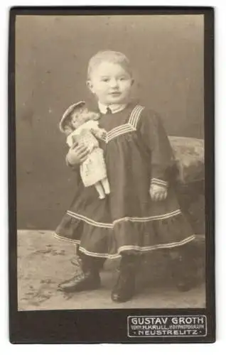 Fotografie Gustav Groth, Neustrelitz, Glambecker Str. 9, Junges Mädchen im schicken Kleid mit Puppe im Arm