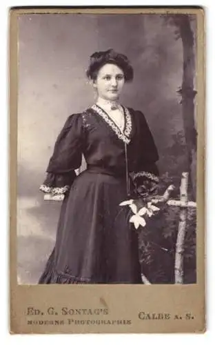 Fotografie Ed. G. Sontag, Calbe a. S., Frau im dunklen Kleid mit Blumen in der Hand