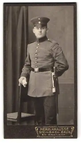 Fotografie Herm. Krausse, Steinbach /Erzgebirge, Am Bahnhof, Porträt eines Soldaten in Uniform