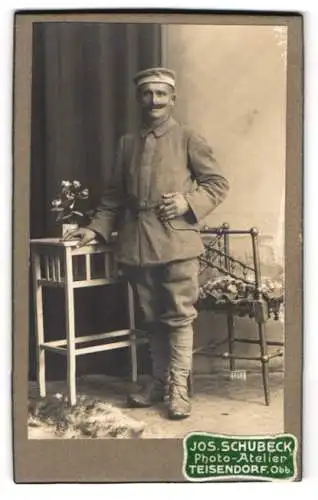 Fotografie Jos. Schubeck, Teisendorf /Obb., Stehender Soldat in Uniform neben einem Tisch mit Blumenvase