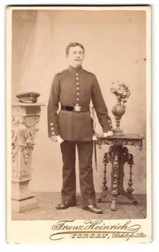 Fotografie Franz Heinrich, Torgau, Schlossstrasse 476, Soldat in Uniform neben einem Tisch mit Blumenvase