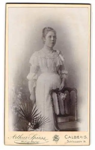 Fotografie Arthur Spiess, Calbe a. S., Schlossstr. 14, Dame im eleganten Kleid neben einem Stuhl