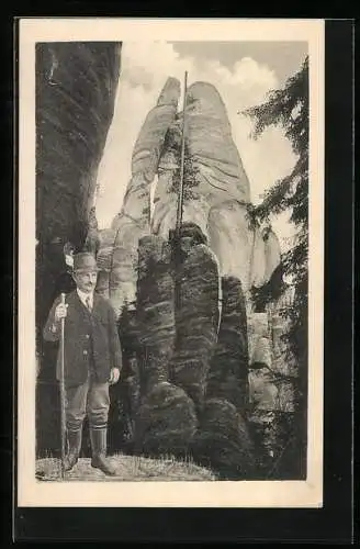 AK Bergsteiger mit Wanderstock vor steilen Felsen