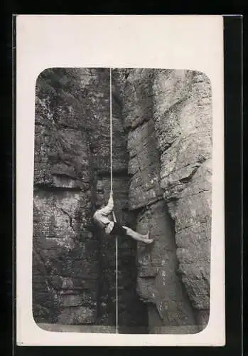 AK Junger Bergsteiger klettert mit einem Seil an einer Felswand