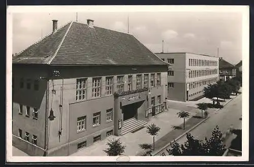 AK Hodonin, Strassenpartie mit repräsentativem Gebäude und Flachdachbau aus der Vogelschau