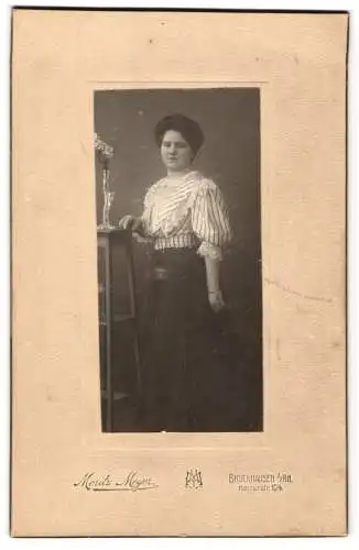 Fotografie Moritz Meyer, Bruckhausen a. Rh., Kaiserstr. 104, Portrait einer Dame neben einem Tisch mit Blumen