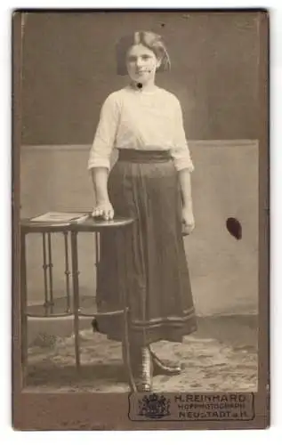 Fotografie H. Reinhard, Neustadt a.H., Eine junge Frau mit Tisch