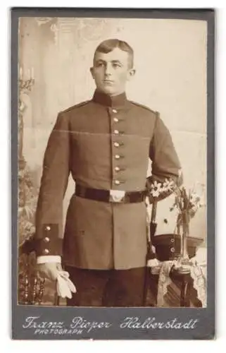Fotografie Franz Pieper, Halberstadt, Stehender Soldat in Uniform mit floralem Arrangement