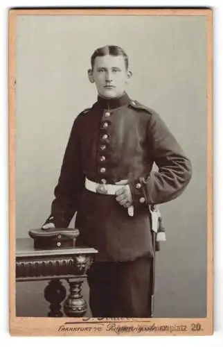 Fotografie P. Krabo, Frankfurt a. O., Regierungsstr. 13, Soldat in Uniform neben einem Tisch mit Mütze