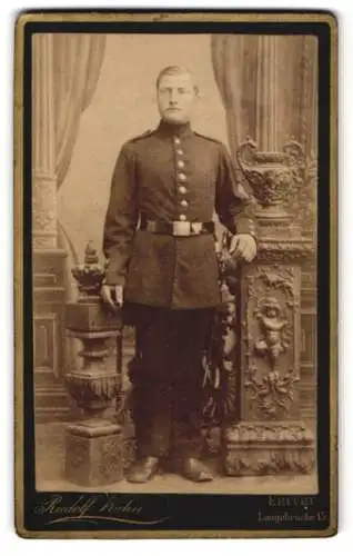 Fotografie Rudolf Kühn, Erfurt, Langebrücke 15, Portrait eines uniformierten Soldaten stehend neben dekorativer Säule