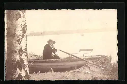 Foto-AK Frau mit Sonnenhut sitzt in einem angelegten Ruderboot