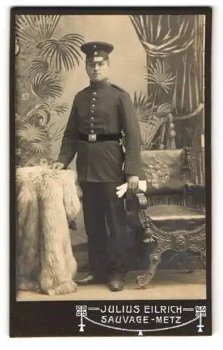 Fotografie Julius Eilrich, Metz, [Soldat in Uniform neben einem kunstvoll verzierten Stuhl