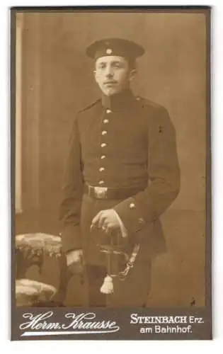 Fotografie Herm. Krausse, Steinbach /Erz., Am Bahnhof, Ein Soldat in Uniform