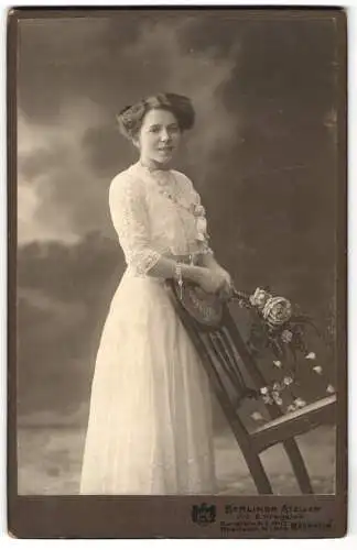 Fotografie Berliner Atelier, Mannheim, Breitestr. 4, Junge Frau in einem weissen Kleid posiert neben einem Stuhl