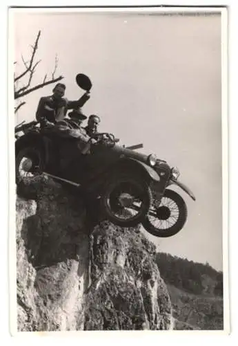 Fotografie unbekannter Fotograf und Ort, Drei Männer in einem von einer Klippe hängenden Automobil Fafnir