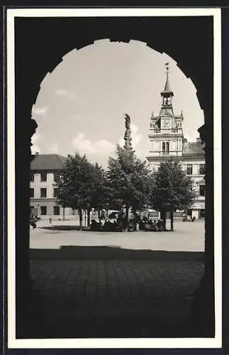 AK Chotzen, Marktplatz, Säulendenkmal, durch ein Tor gesehen