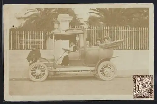 Foto-AK Auto hält vor einem umzäunten Park, Dame am Steuer, Kinder im Fond