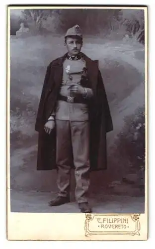 Fotografie E. Filippini, Rovereto, K.u.K. Soldat in Uniform mit Mantel und Schützenschnur