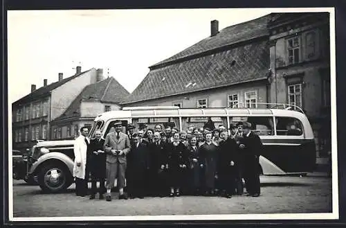 Foto-AK Bus parkt in einer Ortschaft, Reisegruppe posiert für ein Foto