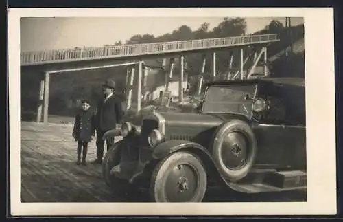 Foto-AK Auto vor einer im Bau befindlichen Brücke, Vater mit Kind am KFZ