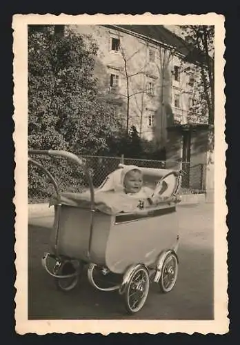 Fotografie unbekannter Fotograf und Ort, kleines Kind schaut aus seinem Kinderwagen