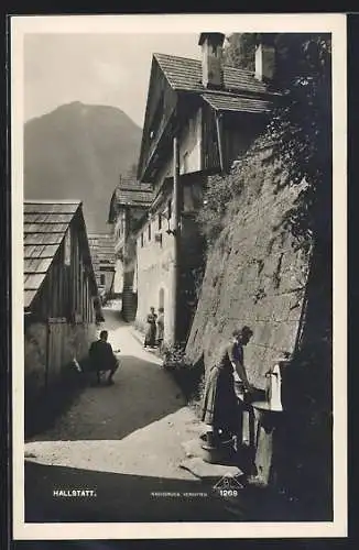 AK Hallstatt, Gassenpartie, Frau an einem Brunnen