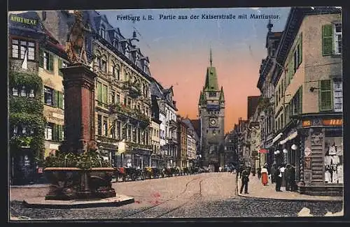 AK Freiburg i. B., Kaiserstrasse mit Geschäften, Martinstor und Brunnen