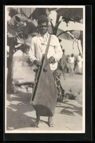 Fotografie Leopold Gabriel, Katanga, Kongolesischer Junge in Hemd und Hose mit einem Instrument