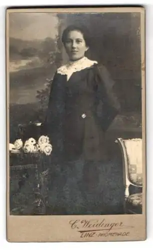 Fotografie C. Weidinger, Linz, Promenade 3, Porträt einer Frau vor einem Tisch mit Blumen