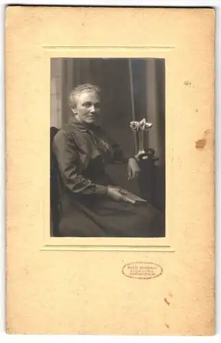 Fotografie Moriz Baumann, Augsburg, Wertachstr., Dame mit Buch sitzend neben einer Vase