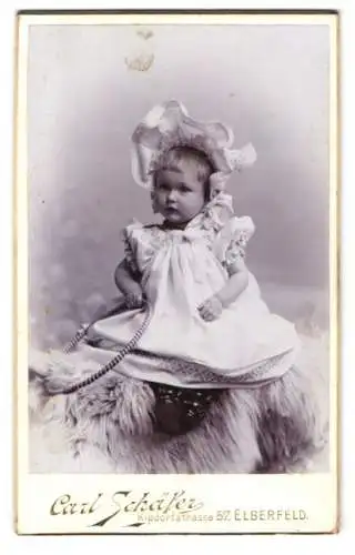 Fotografie Carl Schäfer, Elberfeld, kleines niedliches Mädchen im weissen Kleid mit Haube