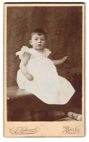 Fotografie C. F. Schmid, Basel, Clarastrasse 5, Kind in weissem Kleid auf einer Bank sitzend