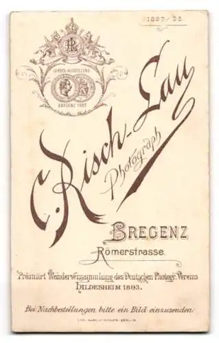 Fotografie C. Risch-Lau, Bregenz, Römerstrasse, Porträt eines jungen Mannes stehend an einem Tisch