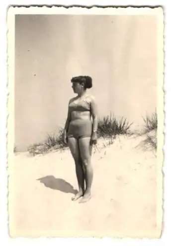 Fotografie beleibte Hausfrau im Badeanzug zwischen Dünen am Strand stehend