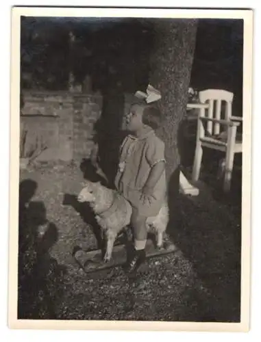 Fotografie niedliches Mädchen Ingeborg auf Spielzeug-Schaf sitzend