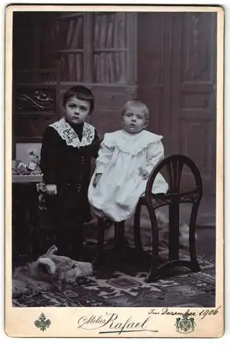 Fotografie Atelier Rafael, Brünn, Neugasse 4, Junger Knabe im Kostüm mit Rüschenkragen neben dem kleinen Bruder, 1906