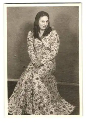 Fotografie hübsche Brünette Frau im langen Kleid mit Blumenmuster und Locken