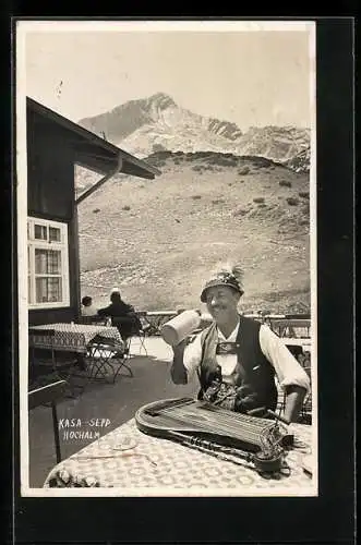 AK Musikant Kasa-Sepp beim Biertrinken vor der Berghütte mit Zither und Aussicht auf die Berge