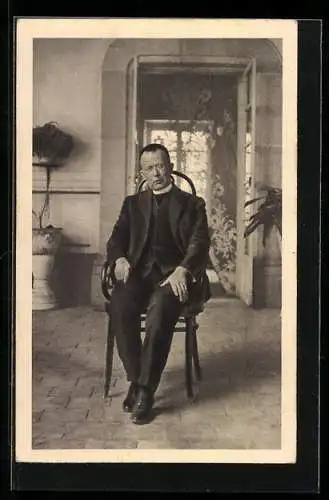 AK Hr. Pfarrer Luis Batis in einem Stuhl sitzend