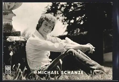 AK Musiker Michael Schanze lächelnd auf einer Wiese sitzend, mit Autograph