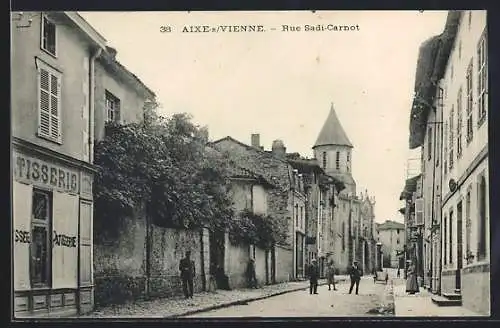 AK Aixe-sur-Vienne, Rue Sadi-Carnot avec pâtisserie et église au fond