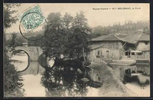 AK Solignac, le Pont et la rivière entourée de maisons et d`arbres