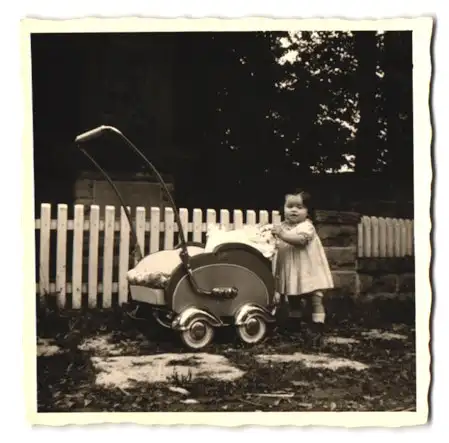 Fotografie kleines Mädchen am Kinderwagen stehend, Baby Buggy