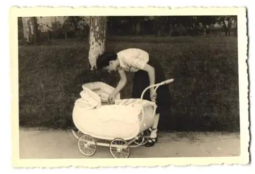 Fotografie Mutter schaut nach ihrem Baby im Kinderwagen