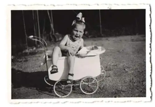 Fotografie schreiendes Mädchen hat sich am Puppenwagen geklemmt