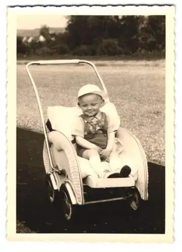 Fotografie verlegen lächelnder Knabe Roland im Kinderwagen sitzend