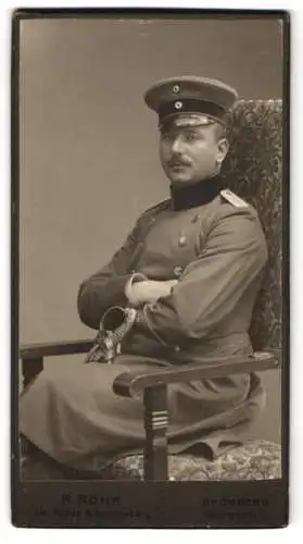 Fotografie R. Röhr, Bromberg, Danzigerstr. 7, Soldat in Uniform mit Mantel, Schirmmütze und Degen