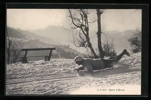 AK Mann rodelt bäuchlings auf einem Schlitten die Piste hinab