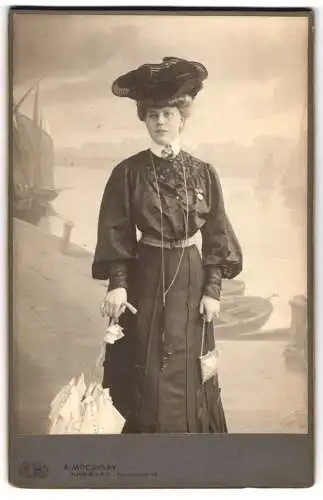 Fotografie A. Mocsigay, Hamburg, Neuenwall 46, elegante Dame mit Hut am Hafen